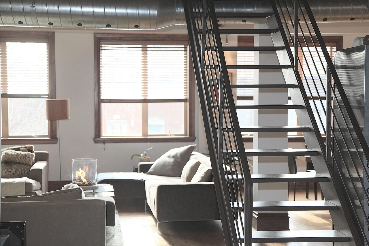 Przestrzenny apartament z dużymi oknami i schodami na drugie piętro.